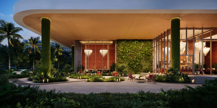 A modern Fort Lauderdale building features large columns covered in greenery, floor-to-ceiling windows, hanging chandeliers, lush landscaping, and outdoor seating under a wooden overhang, surrounded by palm trees and tropical plants at dusk. Lifestyle