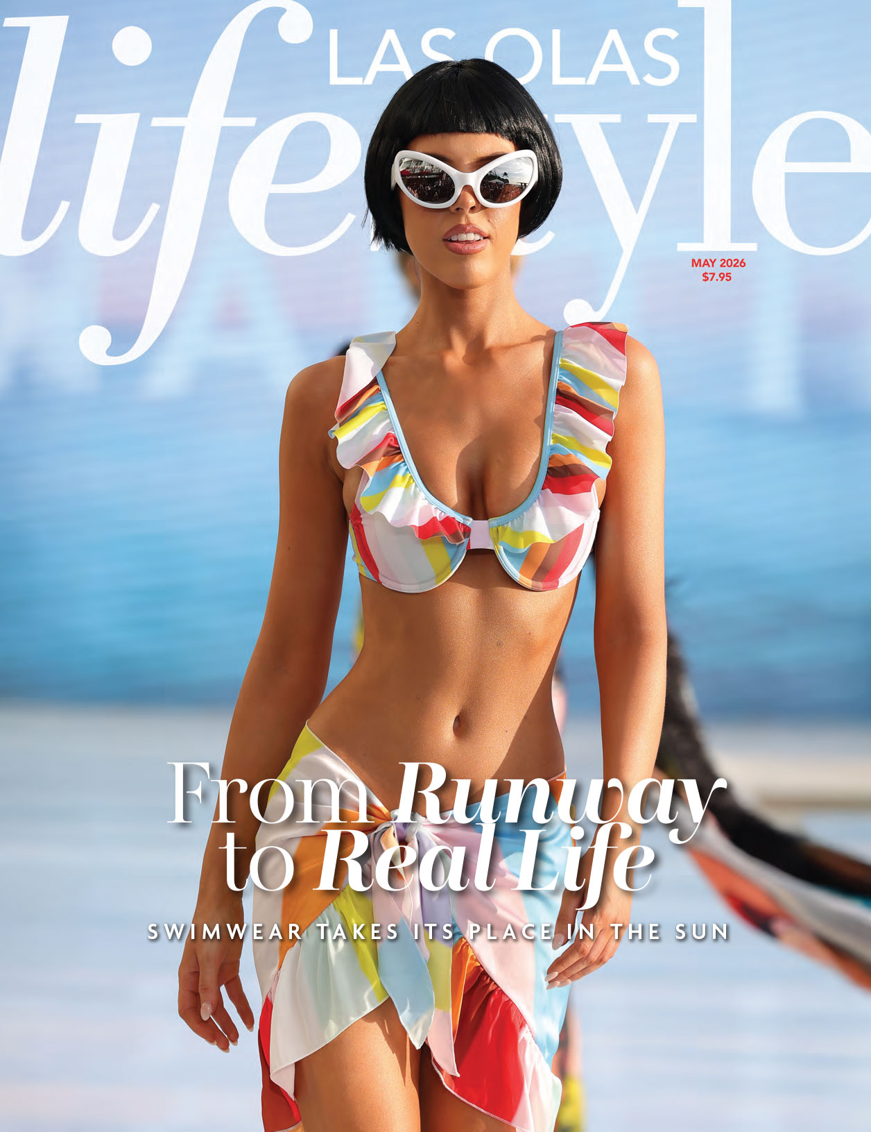 A model wearing a colorful ruffled bikini and white cat-eye sunglasses walks the runway on the cover of Las Olas Lifestyle magazine, May 2026 issue, with the headline "From Runway to Real Life. Lifestyle