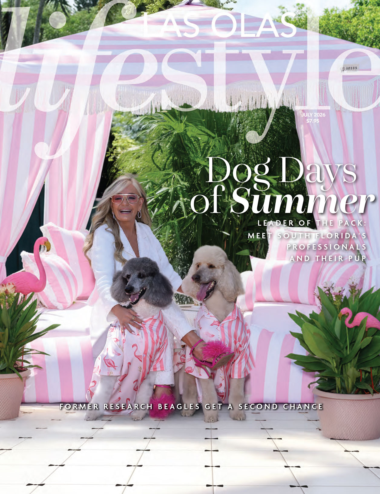 A woman in a white outfit sits between two poodles in matching pink outfits in front of a pink and white striped cabana. The Las Olas Lifestyle July 2026 cover headline reads "Dog Days of Summer. Lifestyle