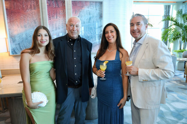 Four adults in formal attire smile for the camera at the Annual Salute to Leadership event hosted by Broward Partnership. The two women hold clutches and drinks, while two men wear blazers. Art and plants can be seen in the background. Lifestyle