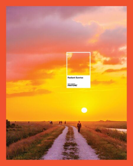A vibrant sunrise with orange and yellow skies painted in place over a grassy path, people walking along it, and a bold red border around the image. A white box in the sky reads "Radiant Sunrise" with the Pantone logo. Lifestyle