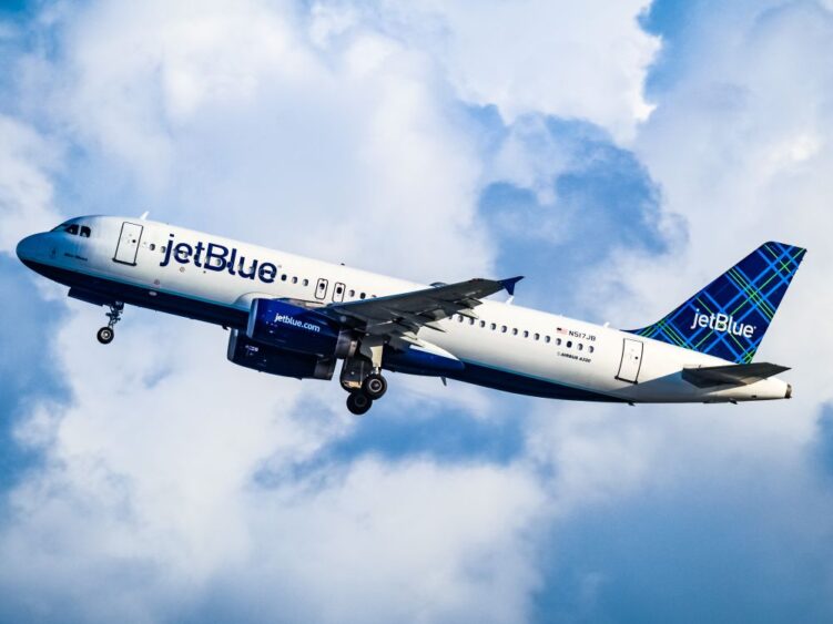 A JetBlue Airbus A320 taking off for a flight to Colombia against a cloudy blue sky. Lifestyle